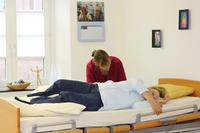 - die pflegende Angehörige hilft die Schritte der gehenden Bewegung Richtung Kopfende zu verstehen